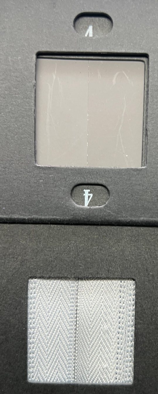 A grey scale card holding a grade 4 reference pair in its upper window and a herringbone twill sample pair in its lower window